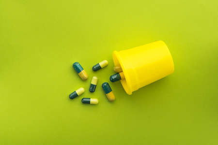 Green and yellow medical capsules on a green background. top or above viewの写真素材