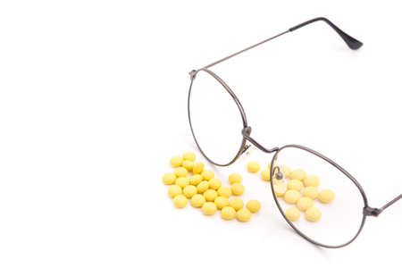 Vision glasses and pills vitamins for improving the eyes. Isolated on a white background.の写真素材