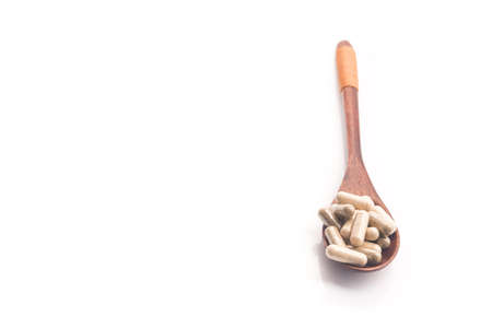 Medical herbal capsules with spoon isolated on white. Natural vitamin additive pills.の写真素材