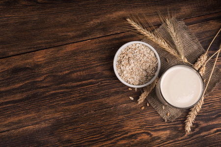 A glass of oat milk and cereal oatmeal on a wooden table. Vegetarian diet concept. top view. place...