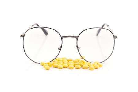 Vision glasses and pills vitamins for improving the eyes. Isolated on a white background.の写真素材