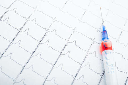 ECG results on paper and red injections to restore heart pulse. Heart attack or hypertensionの写真素材