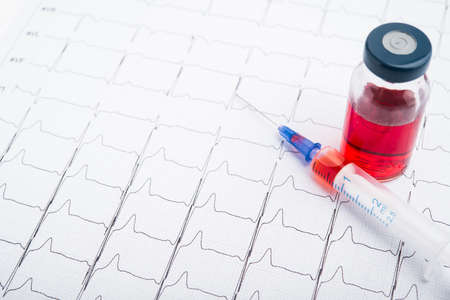 ECG results on paper and red injections to restore heart pulse. Heart attack or hypertensionの写真素材