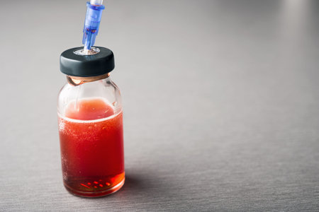Closeup photo of ampule with red medicine and syringe on hospital table. dangerous dose of drugs.