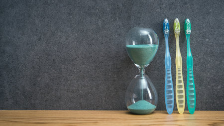 Toothbrushs with hourglass on a bathroom table. dental care and hygiene. banner size. place for...