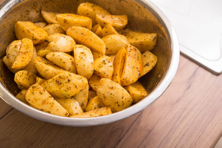 Pieces of pickled potato marinated in spices in bowl.