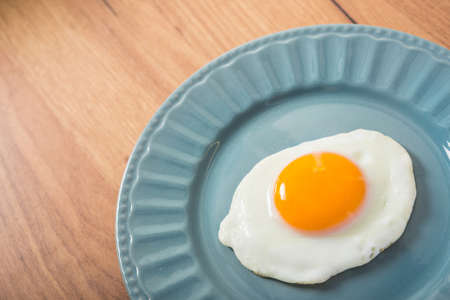 One fried egg on a plate, wood table background.の写真素材