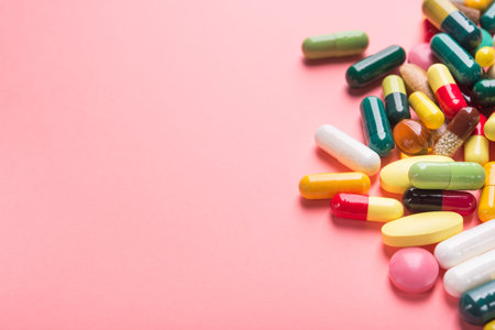 Pile of colored pills, capsule and tablets on a pastel pink background.の写真素材