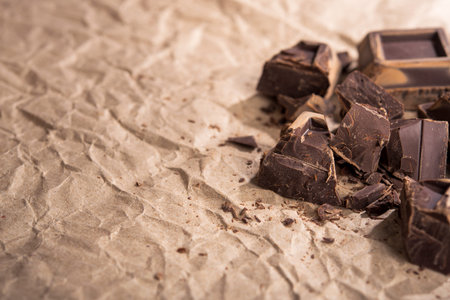 Pieces of tasty black chocolate on a craft paper background. copy space