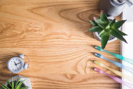 Colored toothbrushs with gray clock on a wooden table. oral hygiene. concept of dental care. top view.の写真素材
