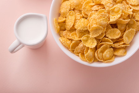 Bowl with cornflakes on a ping pastel background. tasty and healthy morning breakfast. Top view.