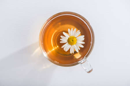 Glass cup with herbal tea with chamomile flowers on a white background. Healthy drink. top viewの写真素材