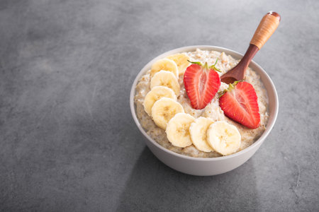 Oatmeal bowl  with banana and strawberry in a stone table. healthy organic food.