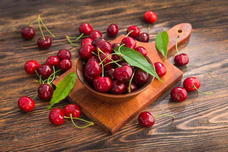 Fresh red cherries with slicing board on a wooden table. Rustic harvest concept. Bio and eco berries.の写真素材