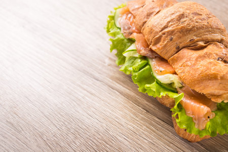 Tasty baked croissants with salmon fish and fresh cucumber on a morning breakfast.の写真素材