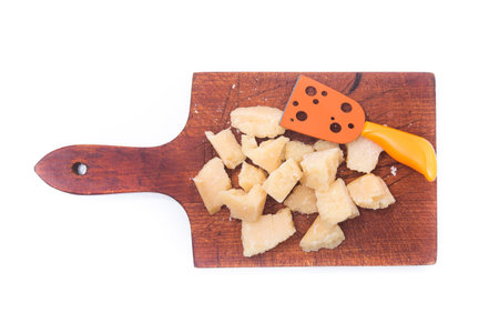 Parmesan cheese pieces on a wooden cut board isolated on a white background. top viewの写真素材