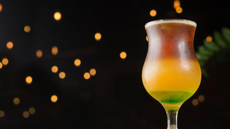 Cold summer caramel coffee cocktail beverage with ice on a cafe table, black lights background.