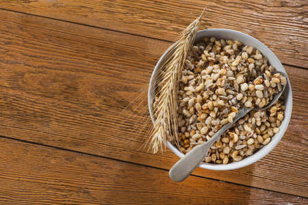 Tasty crispy granola in bowl with seeds and wheat on a wooden table. rustic healthy cereal morning breakfast food. top view. copy space for textの写真素材