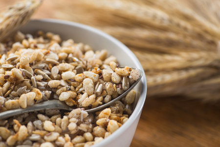 Tasty crispy granola in bowl with seeds and wheat on a wooden table. rustic healthy cereal morning breakfast food.の写真素材