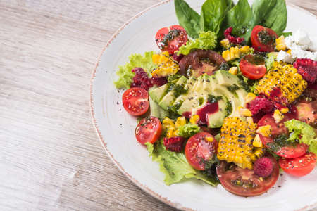 Beautiful display dishes of salad with avocado, corn, tomato and spinach leaves on a table in cafe.の写真素材