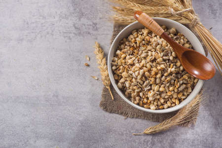 Tasty crispy granola in bowl with seeds and wheat on a stone table. healthy cereal morning breakfast food. top view. copy space for textの写真素材