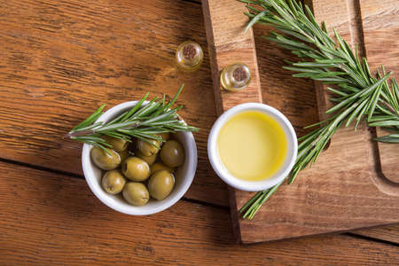 Closeup of  rosemary herb and olive oil in a bowl on a wooden table background. top viewの写真素材