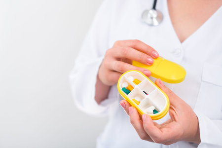 Woman doctor holding yellow pill box with daily medication. medicine and treatment concept background.の写真素材