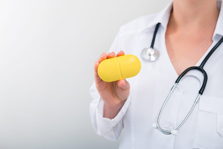 Woman doctor holding yellow pill box with daily medication. medicine and treatment concept background. copy space for textの写真素材