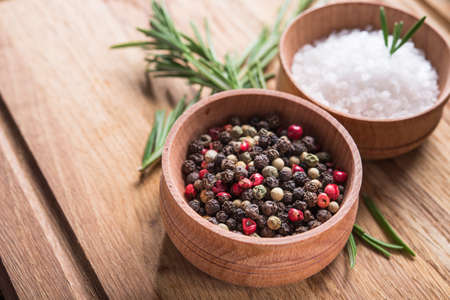 Closeup of spices salt and black papper, rosemary in bowl on a wooden tableの写真素材