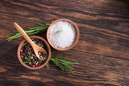 Closeup of spices salt and black papper, rosemary in bowl on a wooden table. top view. copy space for textの写真素材