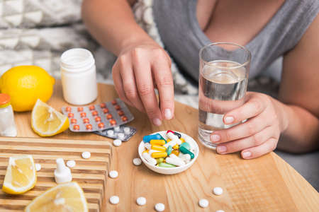 Young woman sick with colds and flu, self-medication at home with vitamins and pills. suffering from the nose due to allergies.の写真素材