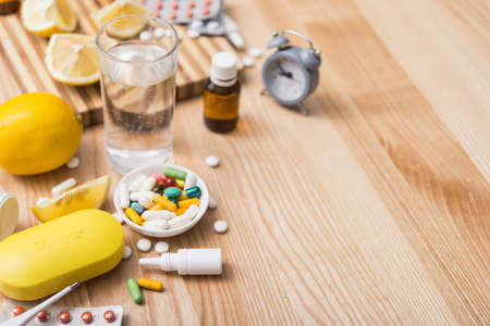Concept of flu treatments with pills, tablets, lemon and thermometer in a home table. copy space for textの写真素材
