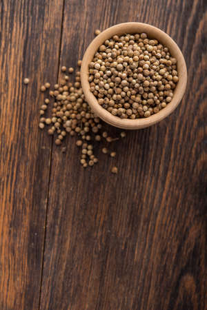 Closeup of coriander seeds in wooden bowl on table. top view. copyspaceの写真素材