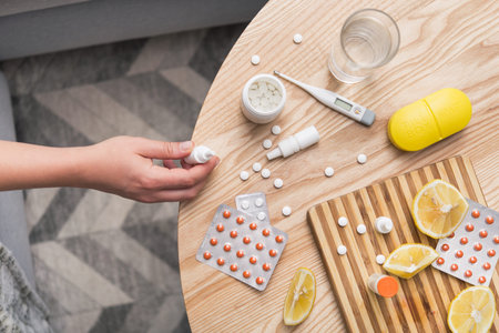 Young woman sick with colds and flu, self-medication at home with vitamins and pills. suffering from...