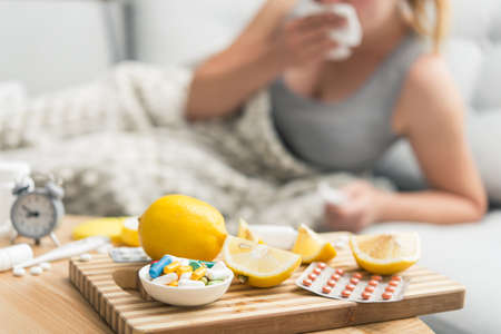 Young woman sick with colds and flu, self-medication at home with vitamins and pills. suffering from the nose due to allergies.の写真素材