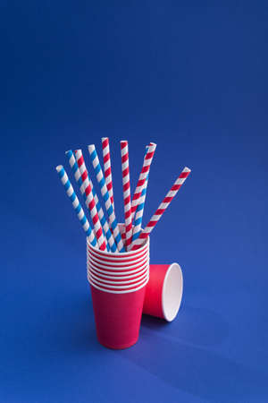 Bright colored cocktail straw in paper cup on a color blue background. recycling eco concept. pop art style.の写真素材
