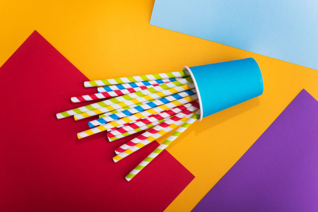 Bright colored cocktail straw in paper cup on a color background. recycling eco concept. pop art...