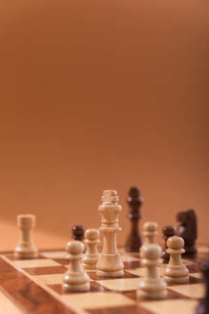 Wooden chess pieces on a chessboard brown background.の写真素材