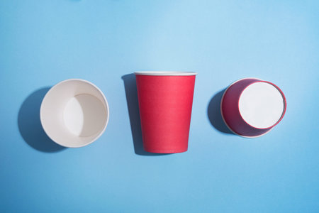 Red paper cup of coffee on a pastel background. Creative pop art. Waste concept. Minimal space.