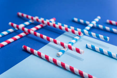 Bright colored cocktail straw in paper cup on a color blue background. recycling eco concept. pop art style.の写真素材