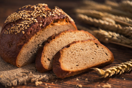 Tasty rye bread with sesame on a wooden background.