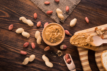 Peanut butter in a bowl on a wooden background. Organic american food. Traditional breakfast.