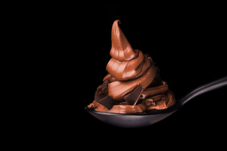 Melted chocolate pile on a spoon isolated on a black background.