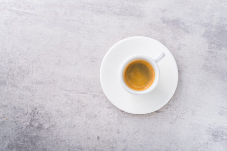 Espresso coffee in a white ceramic cup on a stone gray background. top view