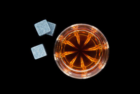 One whiskey glass with stone on a black background. top viewの写真素材