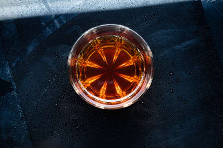 Glass of whiskey on a cold and wet surface of a bar counter.  top viewの写真素材