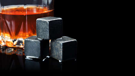 One whiskey glass with stone on a black backgroundの写真素材