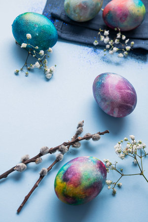 Mystical coloring eggs with spring flowers on a blue background. Easter holiday concept.
