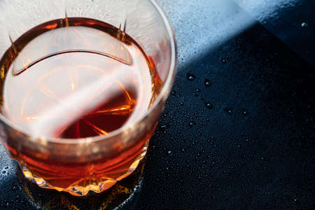 Glass of whiskey on a cold and wet surface of a bar counter.の写真素材