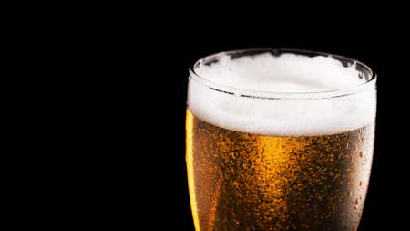 Glass of fresh beer isolated on a black background. Banner size. Wide format.の写真素材